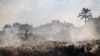 Palestinski dječak mladić prolazi pored gomila tinjajućeg otpada u kampu al-Maghazi, u središnjem Pojasu Gaze, 15. srpnja 2024.