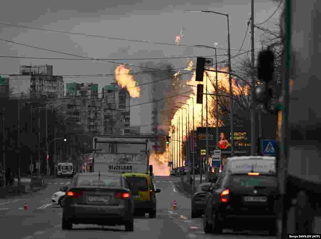 Motorists in the Ukrainian capital drive nearby as Ukrainian firefighters attempt to extinguish a fire after a missile strike. Air raid sirens blared for nearly four hours as many residents sought shelter in the city's subway.