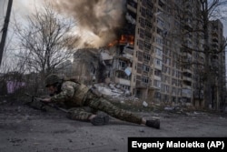 Український поліцейський ховається перед палаючою будівлею після авіаудару військ РФ, 17 березня 2023 року