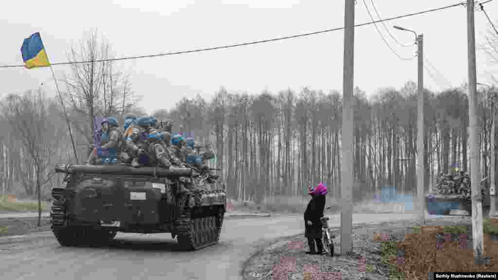 Пожилая женщина приветствует украинских военных, вступающих в город на севере Черниговской области. 2 апреля 2022 года.
