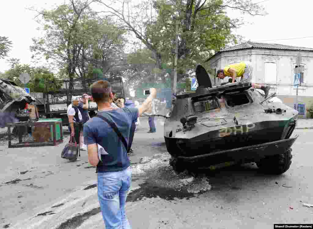 Люди оглядають знищену бронетехніку, якою, ймовірно, користувалися бойовики угруповання «ДНР», що визнане в Україні терористичним. У боях 13 червня загинуло кілька людей, операція завершилася успіхом ЗСУ – Маріуполь було повернено під контроль української влади
