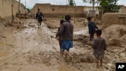 People walk near their damaged homes after heavy flooding in Baghlan Province in northern Afghanistan on May 11. 