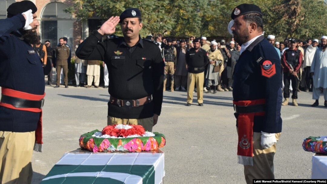 د پولیسو چارواکي د ډېسېمبر پر ۱۸مه په برید کې د وژل شویو ملګرو تر جنازې وروسته تابوتونو ته سلامي کوي. 