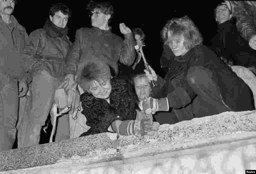 Građani Berlina uzimaju čekiće i ostale alatke, te počinju rastavljati dio Berlinskog zida kod Brandenburške kapije, 9. novembar 1989.