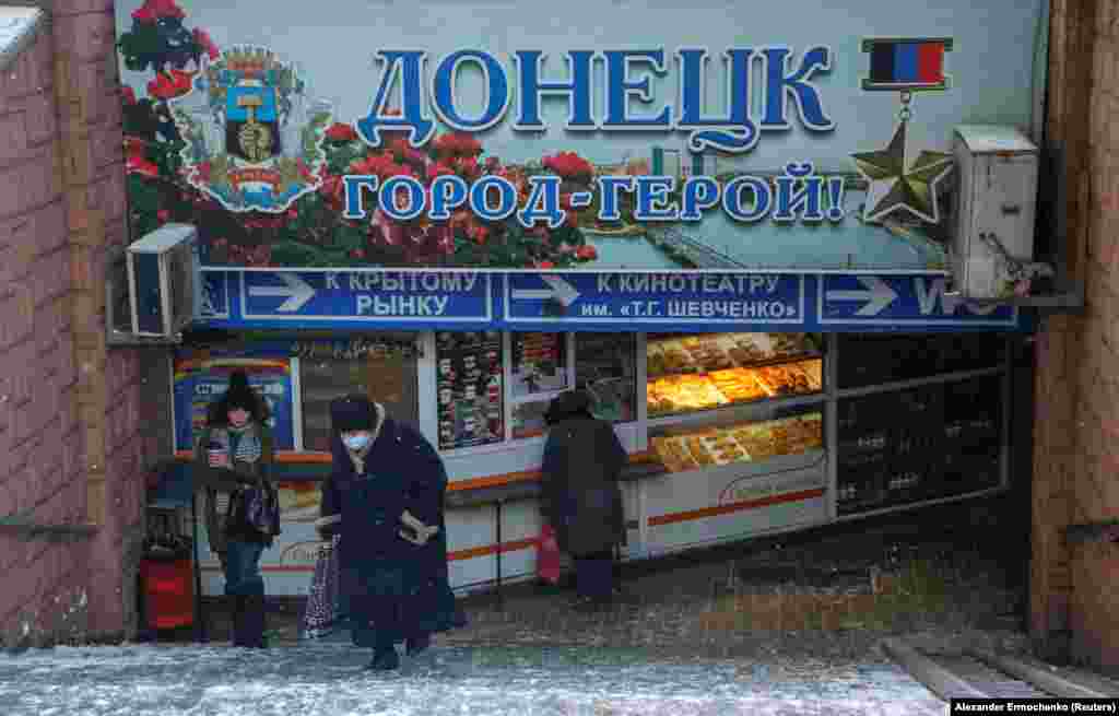 People walk through a pedestrian tunnel under a sign declaring "Donetsk Hero City" in the separatist-held city of Donetsk.