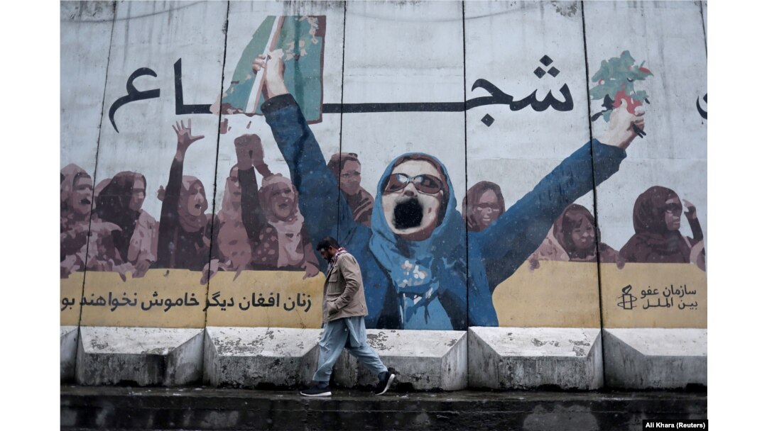 On January 3, a man walks past a mural on the wall of current Ministry for the Promotion of Virtue and Prevention of Vice that says "Brave" at the top and "Afghan women no longer silent" below.