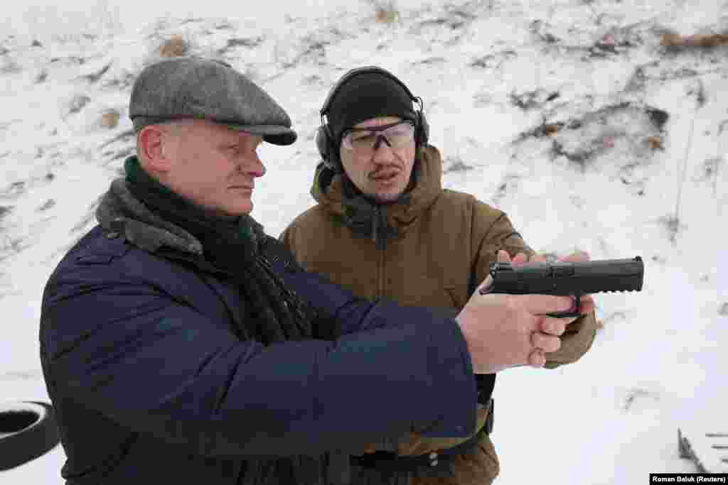 A man handles a pistol during a military training session for workers of "essential city industries and services" near the western Ukrainian city of Lviv on January 25. 