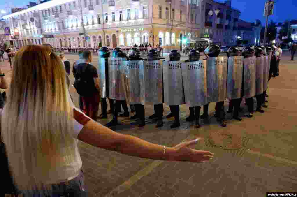 O femeie gesticulează în fața forțelor de ordine în Homel, în 10 august.