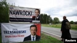 O femeie, trecând pe lângă panouri electorale ale candidaților la alegerile prezidențiale din Polonia, în orașul Pabianice din centrul țării, înainte de turul doi de scrutin, de pe 1 iunie 2025