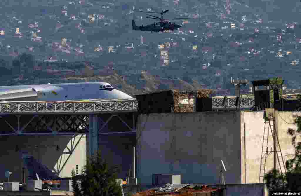 Un elicopter de luptă rusesc patrulează baza aeriană Hmeimim. Bektas spune că nu este clar dacă militarii ruși aduși la baza Hmeimim de pe alte poziții din Siria vor rămâne acolo sau vor fi scoși din țară. O posibilă destinație ar fi Libia.