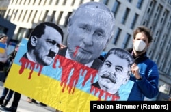 Учасник протесту тримає плакат із зображенням Володимира Путіна, Адольфа Гітлера та Йосипа Сталіна під час антивоєнної демонстрації в Гамбурзі, 20 березня 2022 року