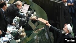 حسن روحانی (راست) در حال ارائه بودجه سال گذشته به رئیس مجلس
