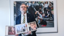 Stephen Capus poses with the photos of RFE/RL imprisoned journalists (L-R) Russia' Nika Novak, Belarus' Ihar Losik and Azerbaijan's Farid Mehralizada