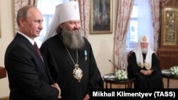 Президент Росії Володимир Путін (ліворуч) під час вручення державної нагороди Росії наміснику Києво-Печерської лаври митрополиту УПЦ (Московського патріархату) Павлу (Лебідю) (другий зліва). Праворуч – патріарх Московський Кирило. Київ, 27 липня 2013 року