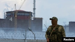 Військовий із російським прапором на формі стоїть біля Запорізької атомної електростанції біля міста Енергодару Запорізької області, 4 серпня 2022 року