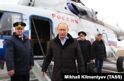 Путін виходить з вертольота на авіабазі Кримськ на півдні Росії в січні 2013 року. На задньому плані офіцер з ядерною валізою віддає честь