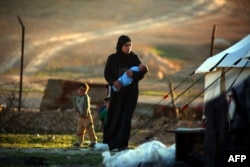 An IS bride carries her child at the refugee camp in the Syrian village of Ain Issa. (file photo)