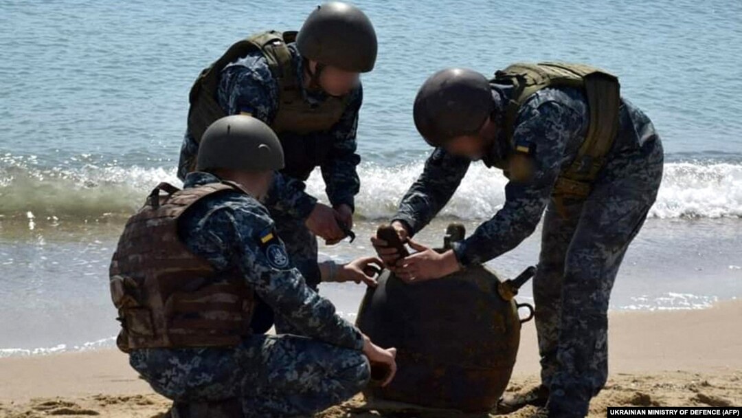 Українські військові знешкоджують морську міну, викинуту на берег штормом, під час масштабного вторгнення Росії до України, травень 2022 року