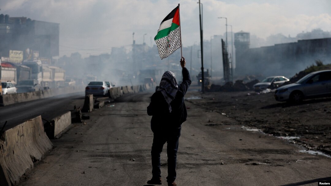 Čovek drži palestinsku zastavu, tokom sukoba Palestinaca s izraelskim snagama na okuipranoj Zapadnoj obali, 27. decembar 2022.