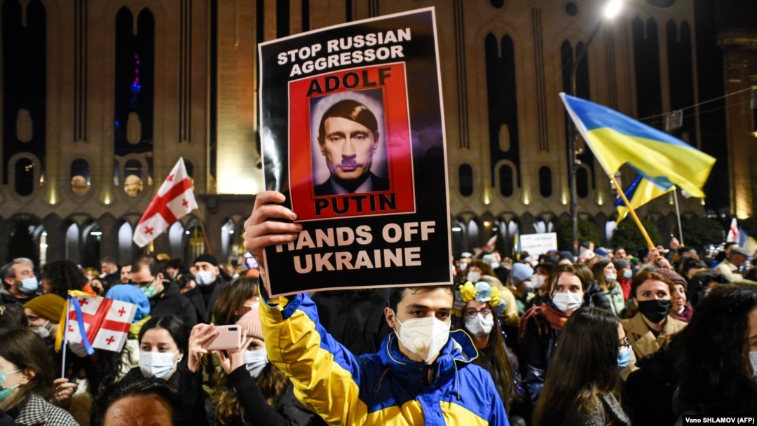 Demonstrators hold up signs and wave flags during a rally in support of Ukraine in Tbilisi on February 28.