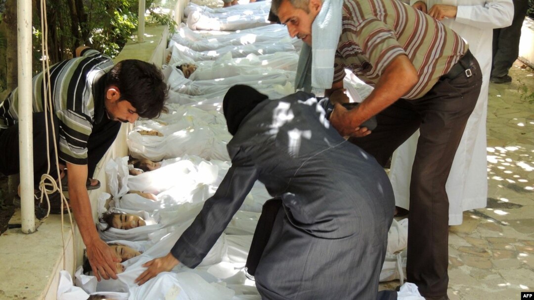 A woman mourns over one of the shrouded bodies of children and other victims that Syrian rebels claim were killed in a toxic gas attack by pro-government forces in eastern Ghouta on August 21.